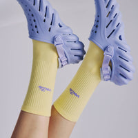 Purple sandals with yellow socks on a plain background